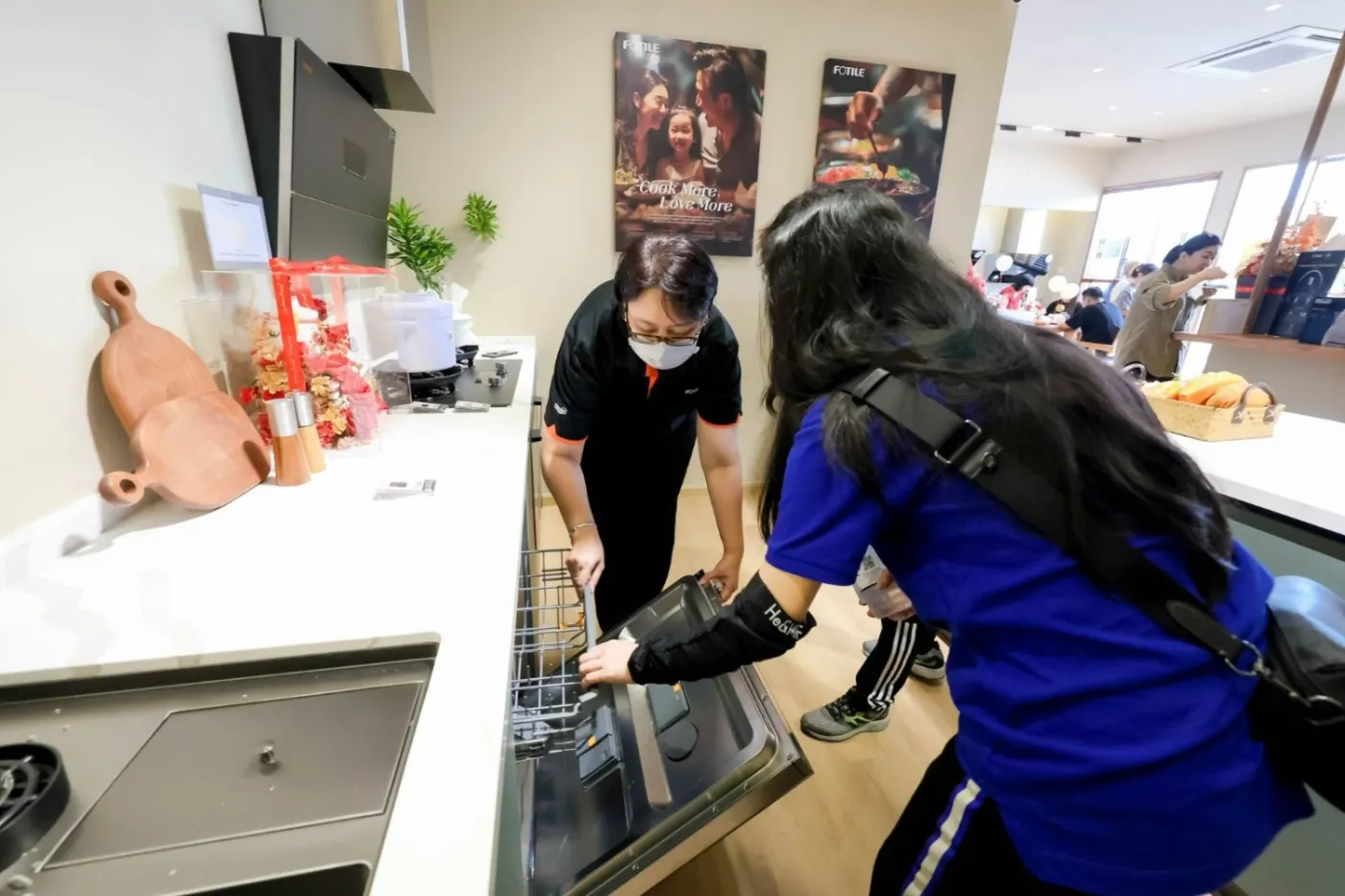 A Cabchen team member showing a visitor a built-in appliance in the showroom