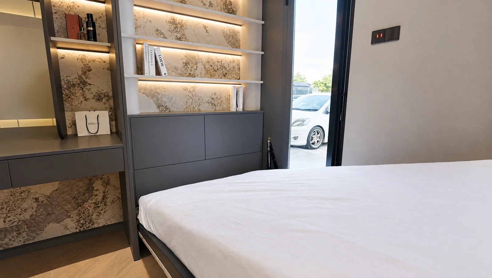 Real Cabchen showroom room with a fold-down wall bed, dark cabinetry and lit display shelves with stone-look backing